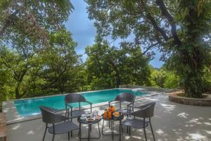 a patio with a table and chairs next to a swimming pool at SaffronStays Hidden Branches -3BR pet-friendly villa with infinity pool & forest views in Khandala in Lonavala