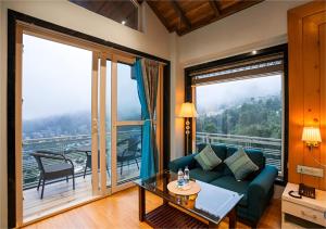 een woonkamer met een bank en een groot raam bij Moustache Select Mcleodganj in Dharamshala