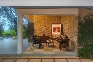 a patio with chairs and tables and a stone wall at SaffronStays Hidden Branches -3BR pet-friendly villa with infinity pool & forest views in Khandala in Lonavala