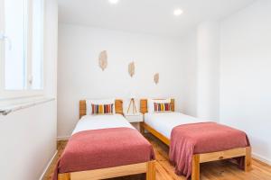 two beds in a room with white walls and wooden floors at CICIOSO flats João de Deus 1 in Évora