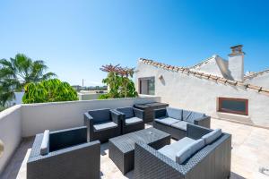 eine Terrasse mit Sofas und Stühlen auf dem Dach in der Unterkunft Villa Serena Marbella - Luxury villa with pool & sea views in Estepona