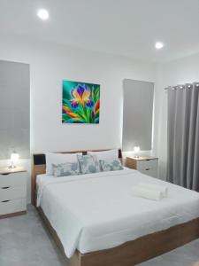 a bedroom with a large white bed and a painting on the wall at Tranquility in Bangrak Beach +20 photos