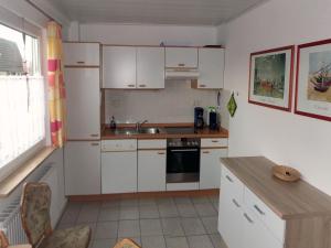 uma cozinha com armários brancos e um lavatório em Ferienwohnung Kapitein em Hooksiel