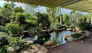 ein Garten mit einem Teich mit Felsen und einer Terrasse in der Unterkunft Bao Ong Thien Retreat - Khu Nghỉ Dưỡng Bào Ông Thiền 