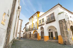 an alley in an old town with yellow and white buildings at CICIOSO flats João de Deus 1 in Évora