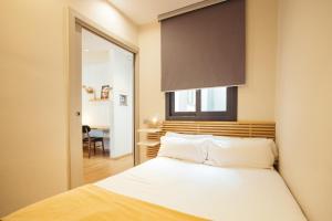 Un dormitorio con una cama con sábanas blancas y una ventana. en Casa Felipa Plaza España, en Barcelona