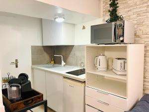 a small kitchen with white cabinets and a microwave at Le Cocon Croix de la Pucelle - 1 chambre in Orléans +3 photos