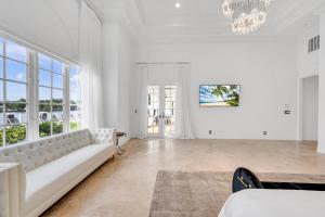 ein weißes Wohnzimmer mit einem Sofa und einem Kronleuchter in der Unterkunft Waterfront Luxury Villa Heated Pool with Afternoon Sun Coral Key in Fort Lauderdale