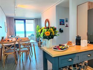 a kitchen and dining room with a table with a vase of flowers at Wavescapes Hang Ten Stay in Cape Town +82 photos