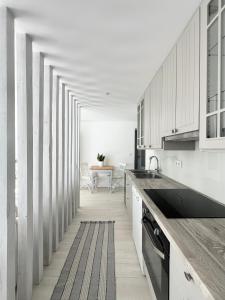 a kitchen with white cabinets and a long hallway at Beach house Estrela do Mar in Vila Chã +50 photos