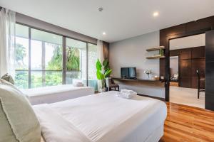 a hotel room with two beds and a television at Majestic 2BR Residence with garden view in Regent in Bang Tao Beach