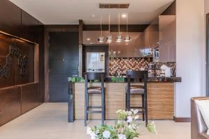 a kitchen with wooden cabinets and a bar with stools at Majestic 2BR Residence with garden view in Regent in Bang Tao Beach