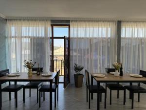 a dining room with two tables and chairs and windows at Hostel Tsalka in Tsalka