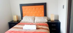 a bed with an orange headboard and two night stands at Casa del Sol in Toluca