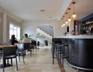 two people sitting at a bar in a restaurant at Hostal Drago in Pueblo Nuevo de Guadiaro