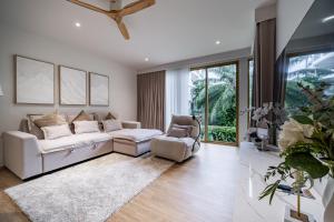 a living room with a white couch and two chairs at Beachside Residences by NLA in Bang Tao Beach