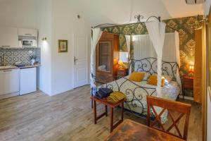 a bedroom with a bed and a table and a kitchen at Mas de la Roule, 4 studios, piscine chauffée, studio SPA, parc 2 ha, Pont d'Avignon à pied in Avignon