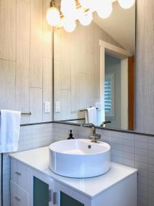 a white bathroom with a sink and a mirror at Bright, Contemporary, Walk To Town & Beach in Eastsound