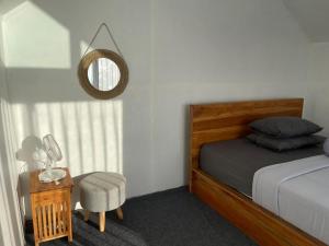 a bedroom with a bed and a chair and a mirror at Alengkong Bali Camp in Kubupenlokan +12 photos
