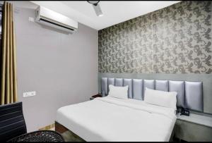 białe łóżko w pokoju ze ścianą w obiekcie Hotel City Star & Restro w mieście Bareli