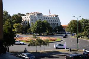a white building with cars parked in a parking lot at La Maman- Only self check-in in Braşov