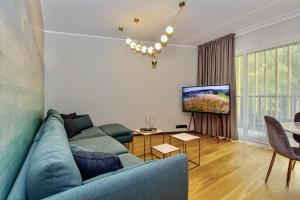 a living room with a blue couch and a tv at Premium Seaside Escape with Forest View and Free Parking in Tallinn