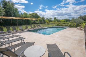 a swimming pool with chairs and a table at Mas de la Roule, 4 studios, piscine chauffée, studio SPA, parc 2 ha, Pont d'Avignon à pied in Avignon