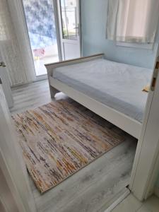 Bett in einem Zimmer mit einem Teppich und einem Fenster in der Unterkunft Çakır villa in Silifke