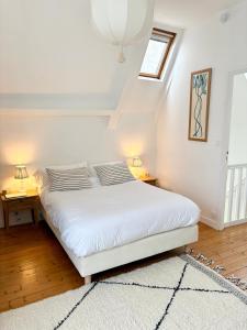 a bedroom with a white bed with two night stands at Jolie maison rénovée au port de Sainte Marine in Combrit