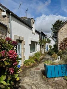 a white house with flowers in a yard at Jolie maison rénovée au port de Sainte Marine in Combrit
