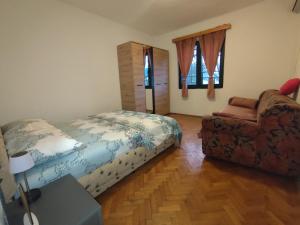 a bedroom with a bed and a couch and a chair at Apartmani Ana Kamenari in Ðurići