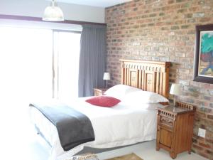 a bedroom with a bed and a brick wall at W21 in Great Brak River