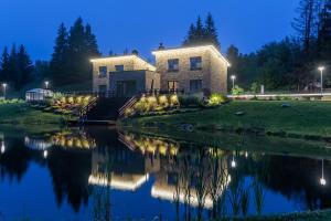 a house on the side of a river at night at Sabos Rezidencija Private Countryside Villa near Vilnius in Dzenkuniskes
