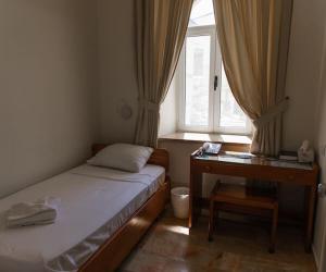 Un dormitorio con una cama y un escritorio y una ventana. en Emanuel Center Guesthouse, en Mashabbe Sade