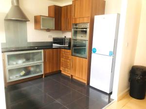 a kitchen with a white refrigerator and wooden cabinets at Ground Floor Beach Front Apartment in Swansea +7 photos