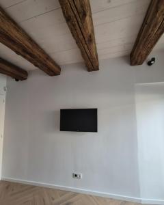 a tv on a white wall in a room with wooden beams at La Lanterne in Saint-Hippolyte