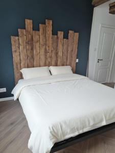 a bedroom with a large white bed with a wooden headboard at La Lanterne in Saint-Hippolyte