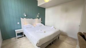 a bedroom with a white bed with a green wall at Magnifique villa avec piscine chauffée au centre du village in Saint-Martin-de-Ré +11 photos