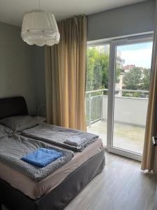 a bedroom with a bed and a sliding glass door at Modern flat close to the beach in Świnoujście