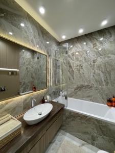 a bathroom with a sink and a tub and a mirror at Capital Park in Astana