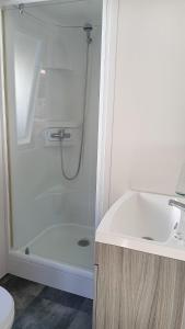 a white bathroom with a shower and a sink at Camping Costa da Morte in Zas