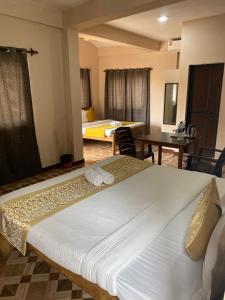 a hotel room with two beds and a table at Hotel The Calangute Central in Baga