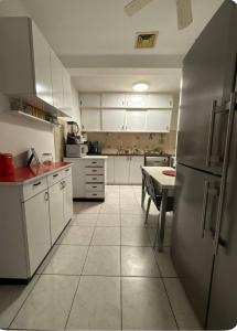 eine Küche mit weißen Schränken und einem Edelstahlkühlschrank in der Unterkunft Cottage near the beach in Kesar Shenaryahu