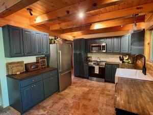 a kitchen with blue cabinets and a stainless steel refrigerator at Perfect Vermont Battenkill Log Cabin in Arlington