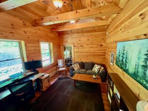 a living room with a large tv in a wooden cabin at Perfect Vermont Battenkill Log Cabin in Arlington