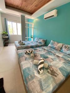 two beds in a room with blue walls at TEZA by the Z - Beachfront Vacation Villa Rental in Ocoy