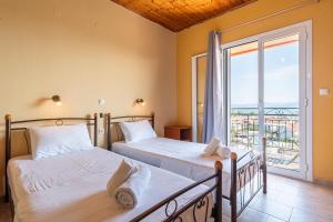 Dos camas en una habitación con una gran ventana. en Gavriil Apartments, en Corfu 40 fotos más