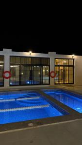 a large swimming pool at night with two red circles at olive tree farm and chalet - مزرعه و شاليه شجره الزيتون 
