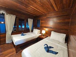 zwei Betten in einem Zimmer mit zwei blauen Schwänen darauf in der Unterkunft Andau Dive Resort Raja Ampat in Tapokreng