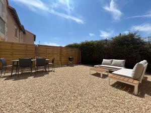 a patio with chairs and a couch and a table at Le cocon familial - 8min du Futuroscope in Avanton